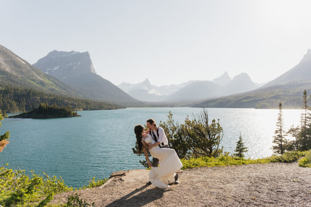 Groom dips bride with huge landscape shot of the mountains at Sun Point Glacier National park