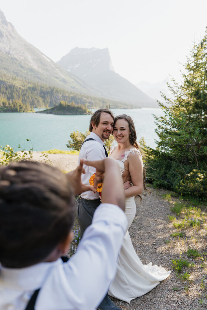 Aiden holds up finger to frame a photo of the bride and groom.