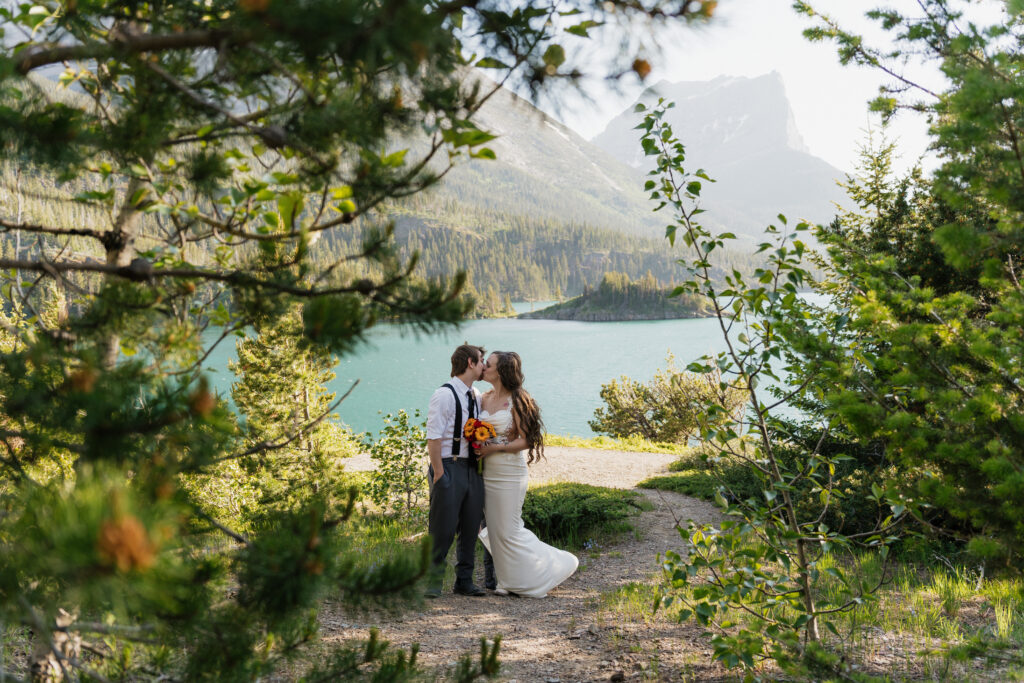 Bride and groom kiss in front of the lake at Sun Point, Glacier National Park