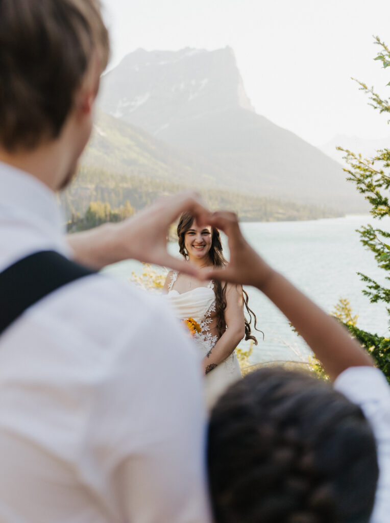 Groom and Aiden hold up a heart to frame the bride.