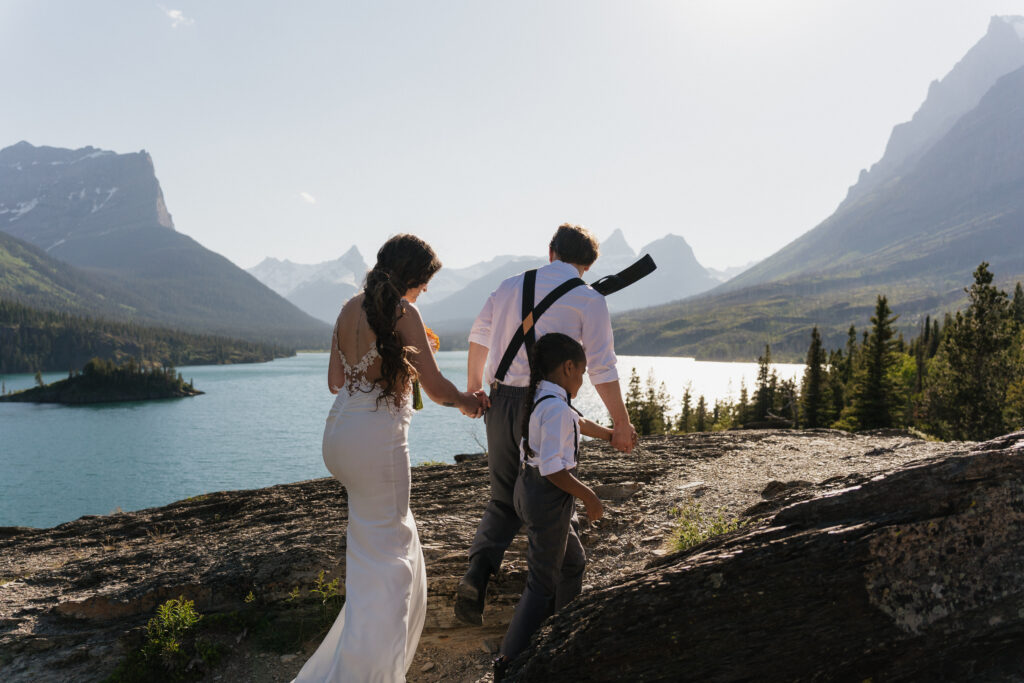 Bree, Will, and Aiden holding hands and walking to the rock at Sun Point in Glacier National Park.