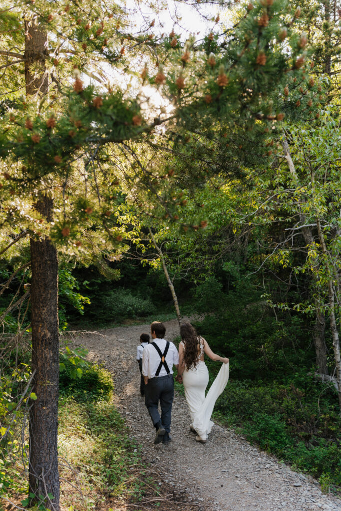 Family walks down path in wedding attire at Glacier National Park.