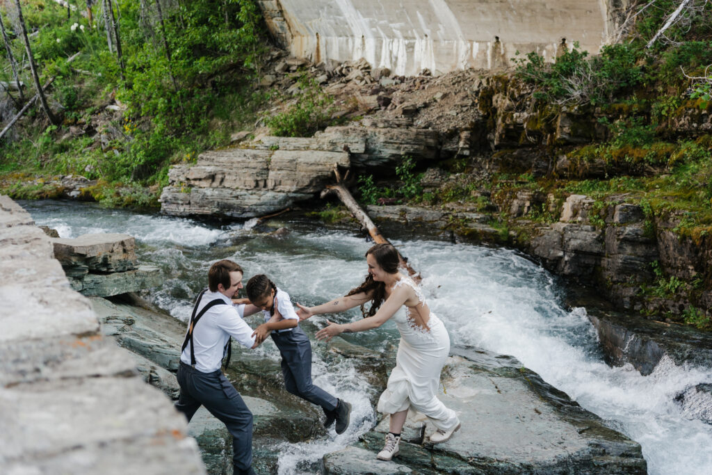 The family exploring the waterfall after eloping at Sun Point in Glacier National Park.