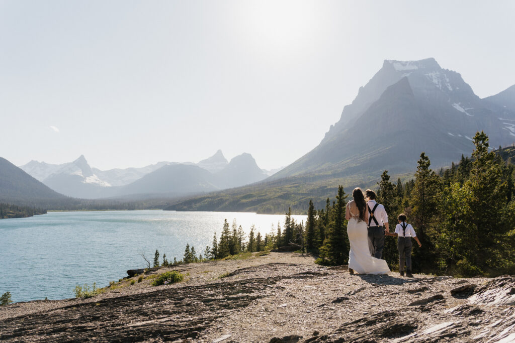Bree, Will, and Aiden holding hands and walking to the rock at Sun Point in Glacier National Park.