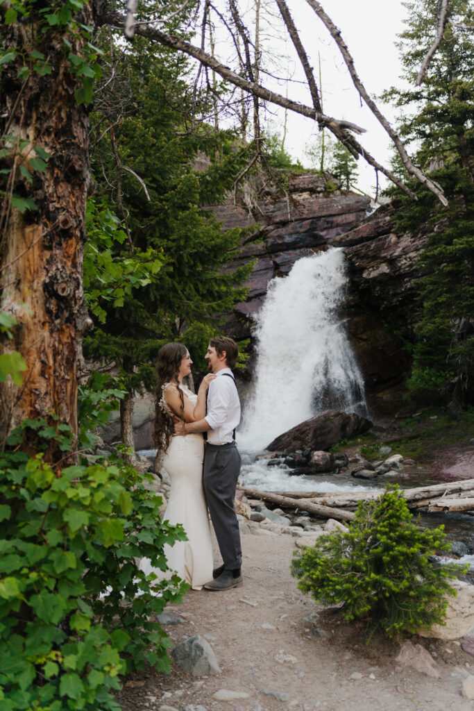 Bride and groom exploring the Baring Falls after eloping at Sun Point in Glacier National Park.