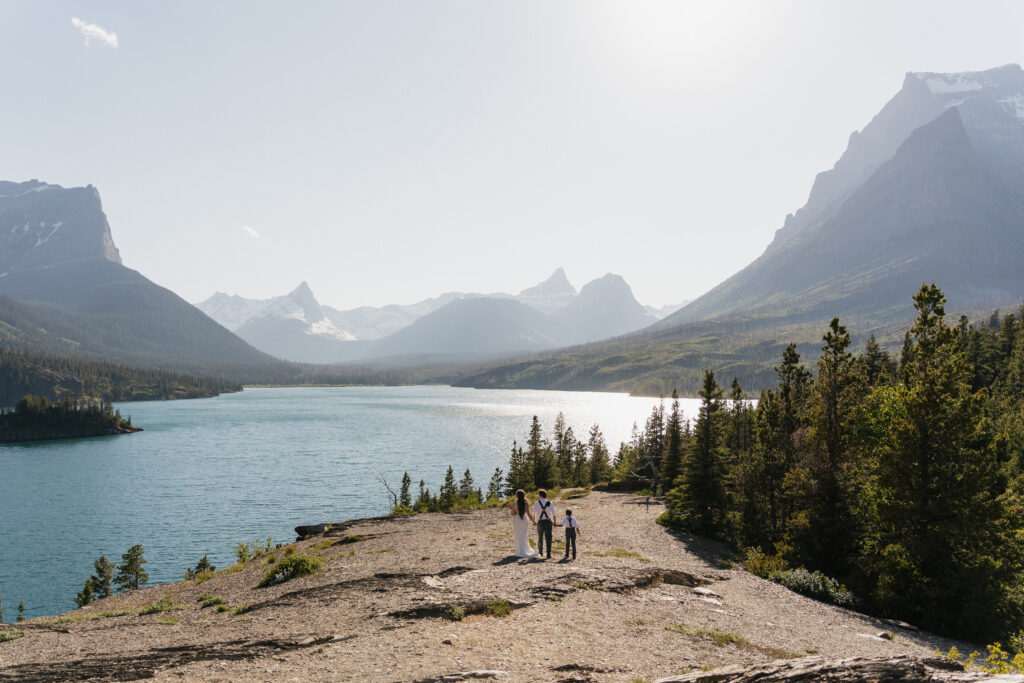 Bree, Will, and Aiden holding hands and walking to the rock at Sun Point in Glacier National Park.