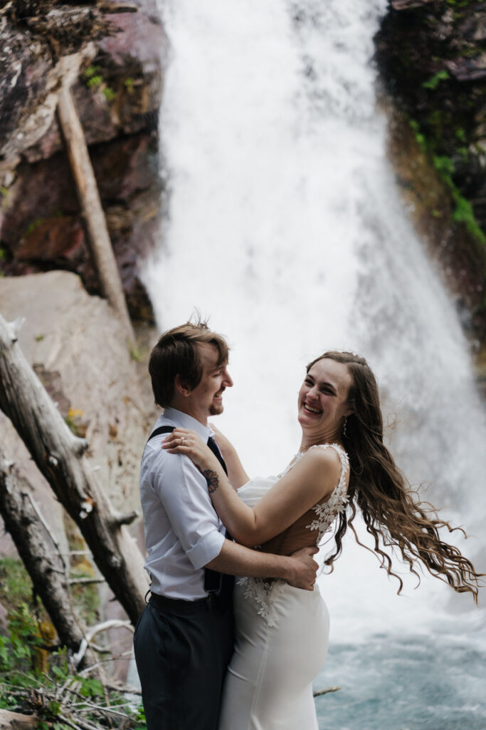 Bride and groom exploring the Baring Falls after eloping at Sun Point in Glacier National Park.