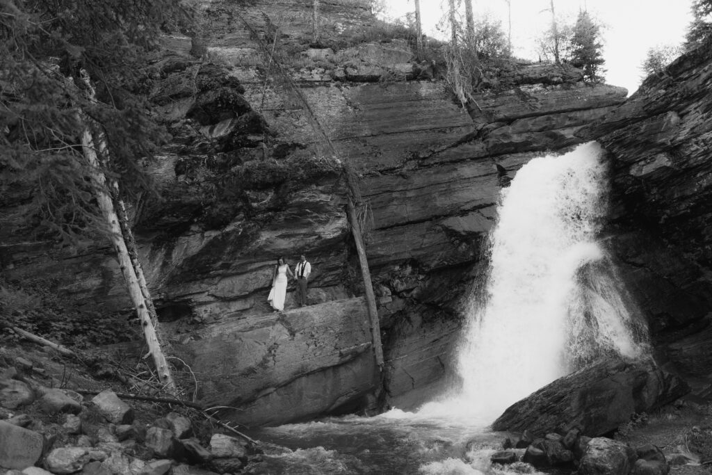 Bride and groom exploring the Baring Falls after eloping at Sun Point in Glacier National Park.