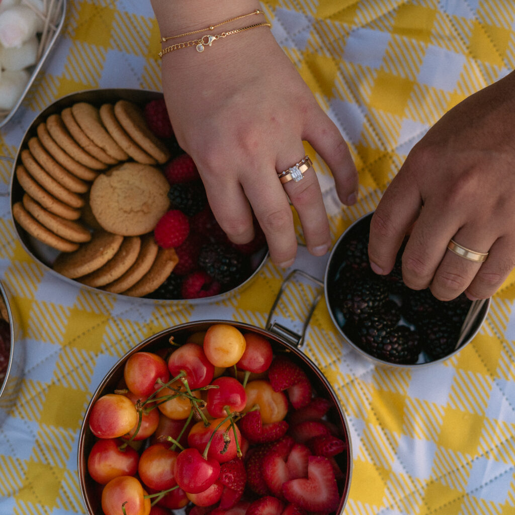 Hands with wedding rings reaching for fruit in Lake McDonald.