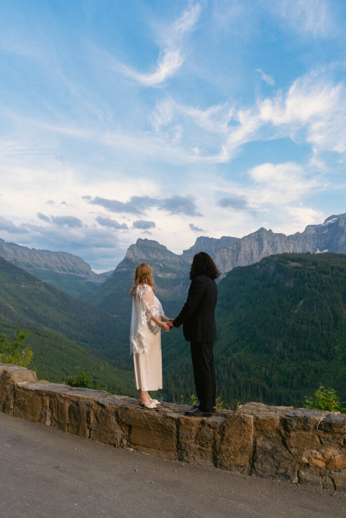 Bride and groom standing on the edge of Going to The Sun Road in Glacier National park.