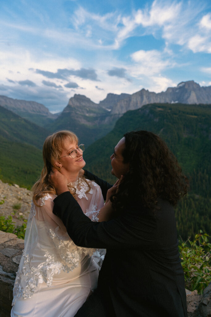 Bride and groom sitting on the edge of Going to The Sun Road in Glacier National park.