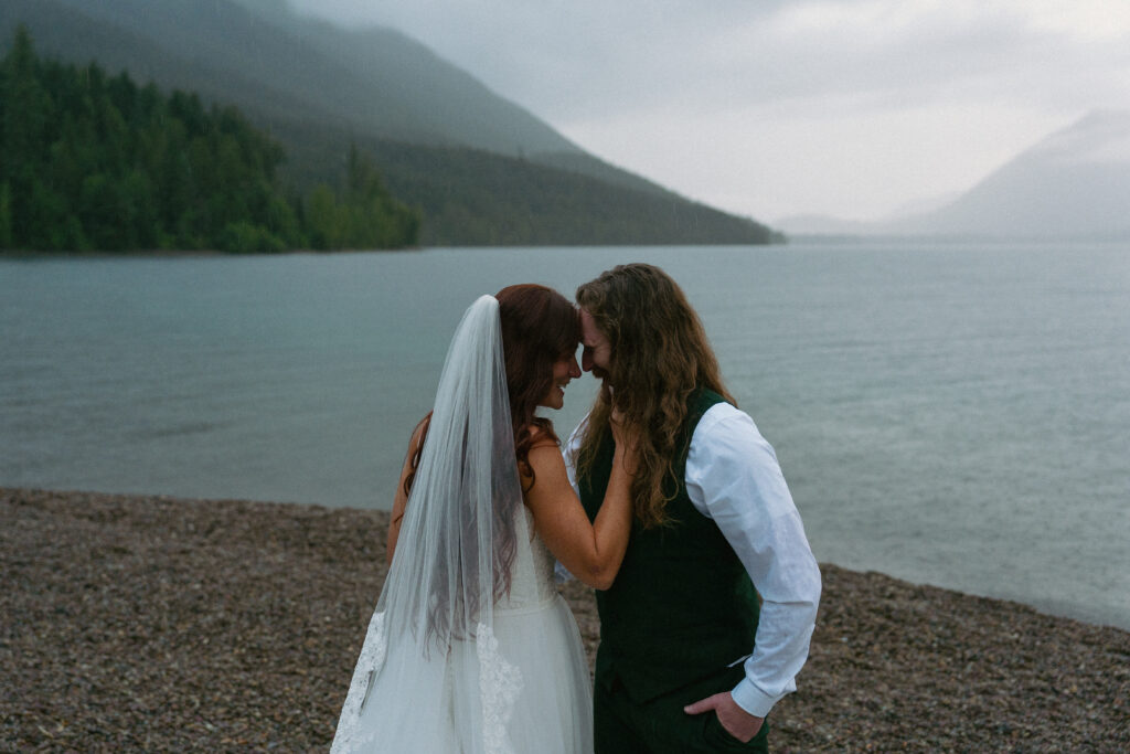 Couple touching foreheads together overlooking a foggy Lake McDonand in Glacier National Park
