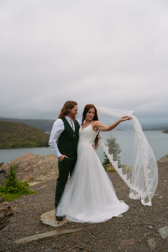 Bride in grooms arms while holding veil in the wind at Glacier National Park