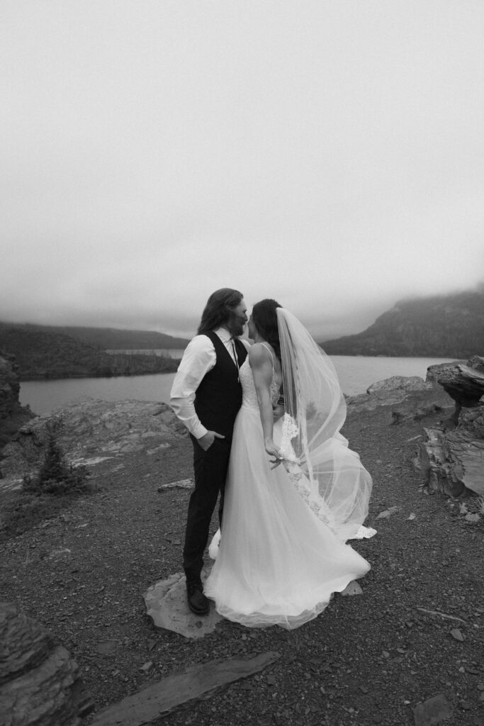 Couple laughing in the wind at Glacier National Park but in black and white.