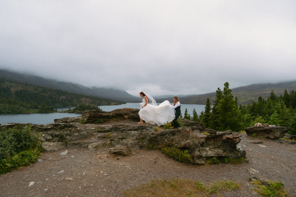 Couple walking in the wind over large rocks at Glacier National Park