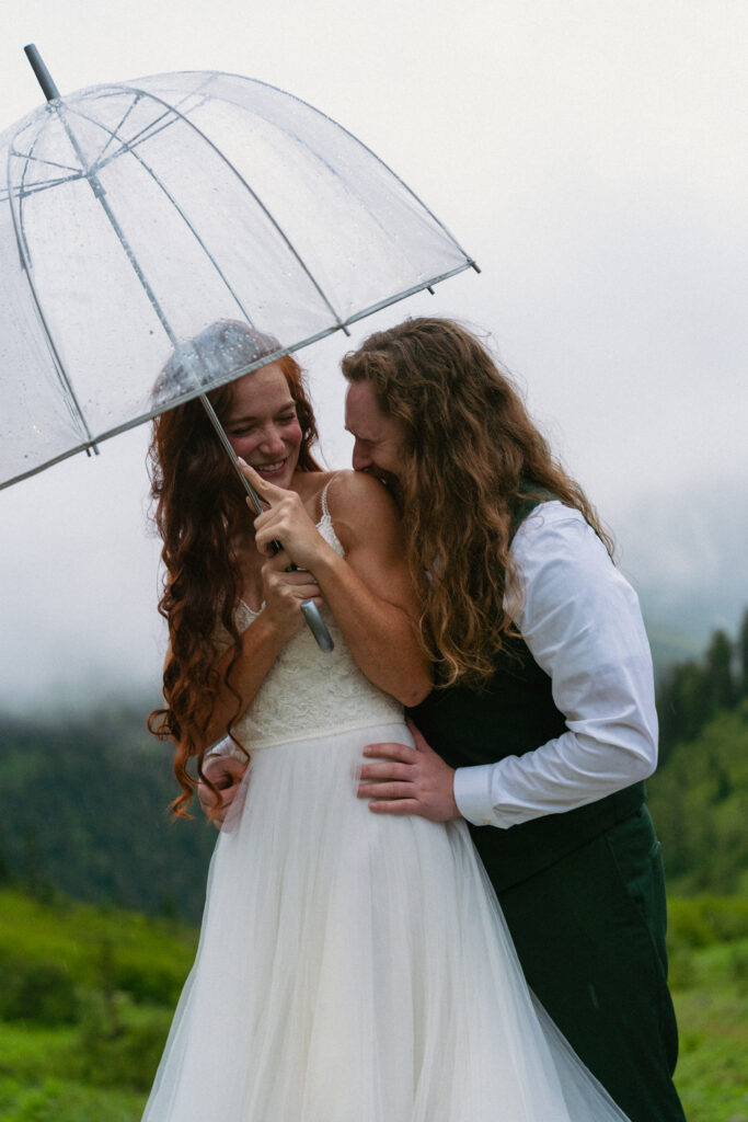Couple posing under an umbrella at a foggy spot on Going to the Sun Road at Glacier National Park