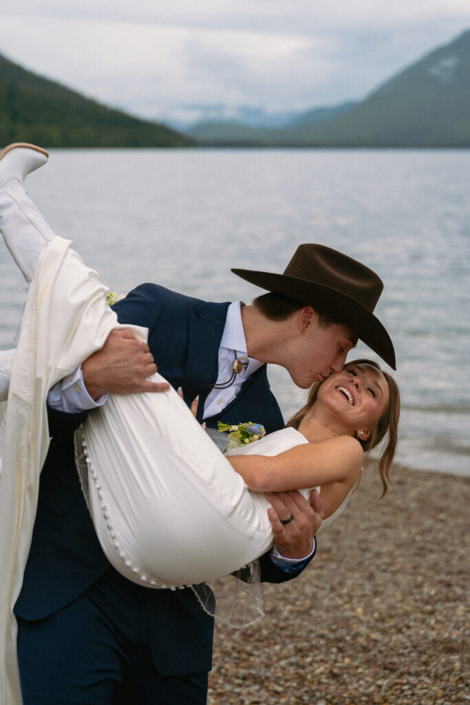 Couple do a dip after elopement ceremony on Lake McDonald beach in Glacier National Park.