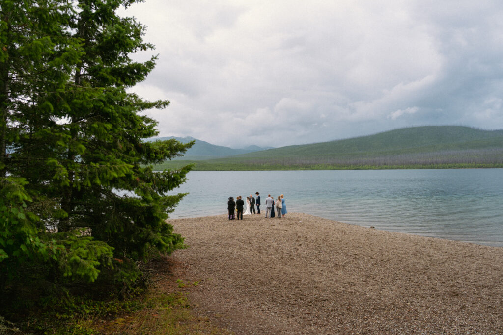 Group gather for an elopement ceremony on Lake McDonald beach in Glacier National Park.